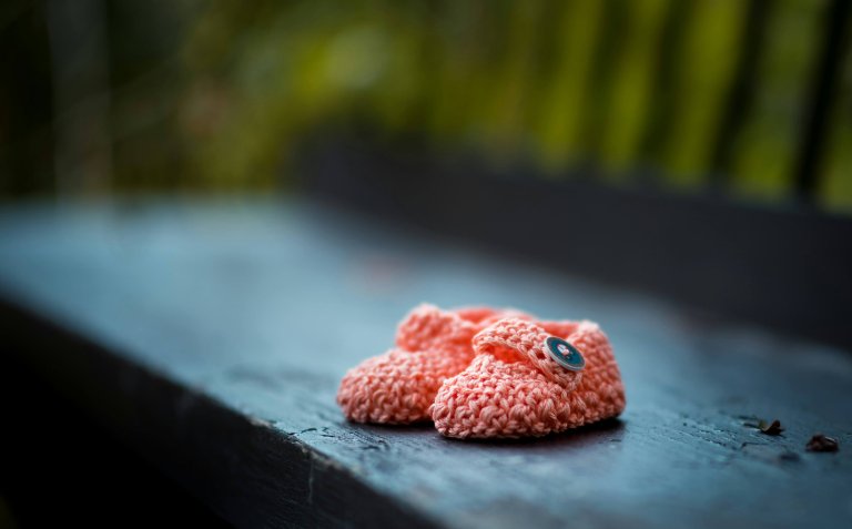 knitted baby booties on a bench
